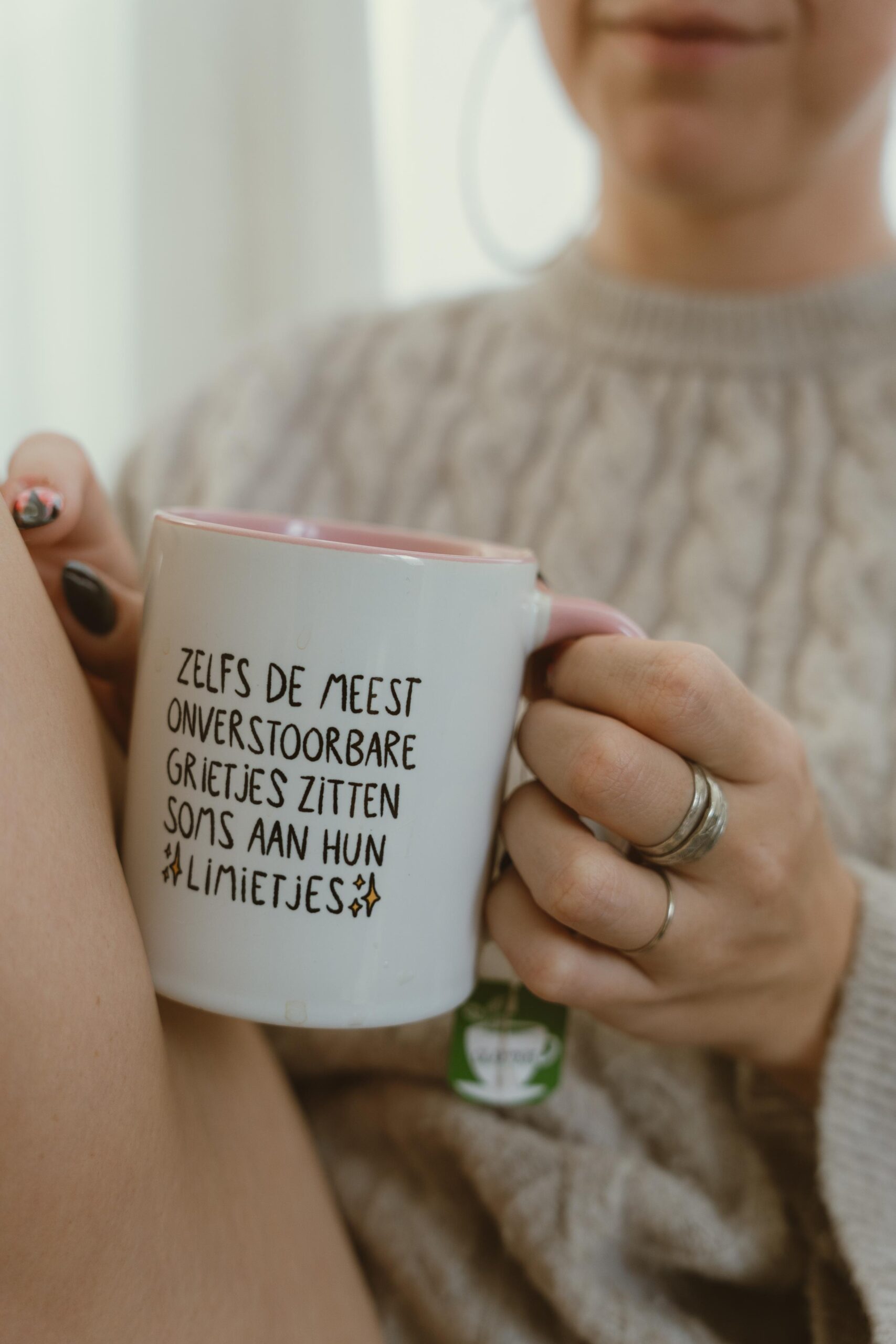 Ayke zit in de zetel met een koffiemok